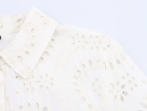 Close-up of intricate geometric embroidery on white shirt collar and shoulder fabric