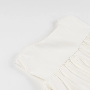 Close-up of white summer tank top showing textured cotton fabric and pleated details