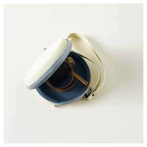 Foldable kids sunglasses with amber frames in a minimalist cream round zipper case