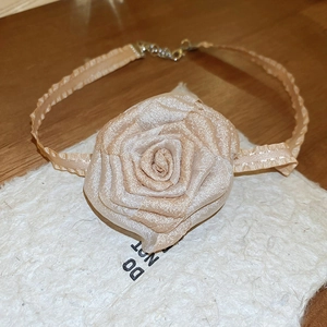Gros plan détaillé d'un collier ras du cou vintage à rose beige en tissu et métal