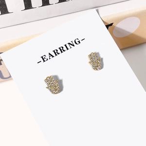 Golden Hamsa hand stud earrings with micro-set zircons on white jewelry card