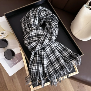 Detail of classic black and white plaid scarf with fringe on a luxury tray with accessories