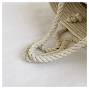 Close-up of the cream-colored woven cotton rope handle with natural tassel detail
