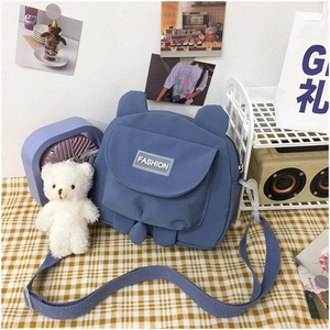 Detail of navy canvas crossbody bag with bear ears, plush charm and fashion front pocket