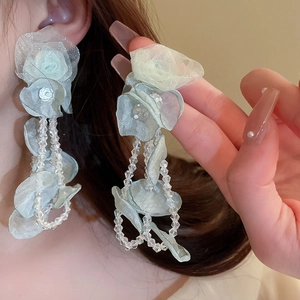 Détail de boucles d'oreilles fleurs en organza vert clair avec pampilles en cristal