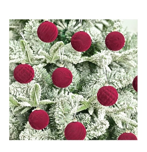 Detail of red velvet flocked Christmas balls with embossed textures on snowy pine branches