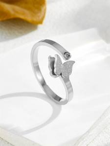 Macro detail of silver butterfly ring with frosted texture and small rhinestone accents