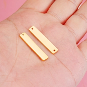 Pair of gold-tone rectangular stainless steel tag pendants with double holes on palm