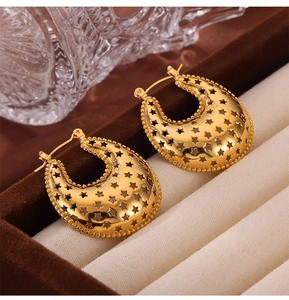 Close-up of gold-plated titanium earrings featuring hollow star patterns on a velvet tray