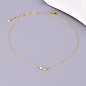 Detail of 18K gold plated stainless steel dolphin pendant with a small pearl pearl accent