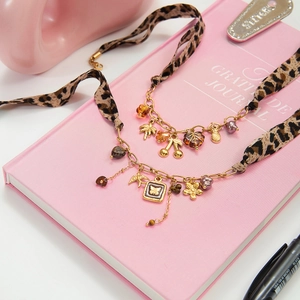 Détail de colliers en ruban léopard avec pendentifs dorés et perles colorées sur livre