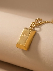 Macro shot of 18k gold plated bar pendant with brushed finish and LOVE engraving