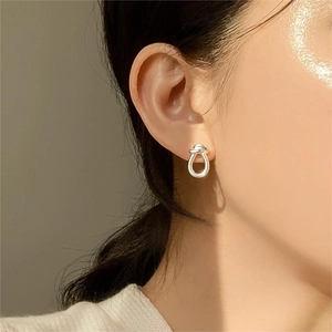 Close-up of minimalist silver knot stud earrings worn by a model for an elegant look