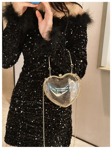 Fashionable transparent acrylic heart-shaped clutch bag with golden chain strap on model