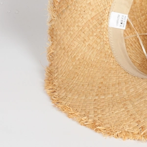 Close-up of 100% raffia straw hat texture with fringe edge and interior brand label