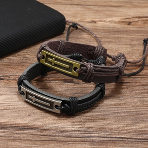 Detail of two layered woven leather cross bracelets in brown and black on wood background