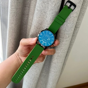 Detail view of quartz watch with blue dial and green silicone strap held in hand