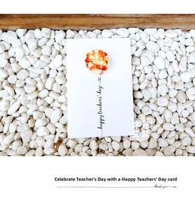 Detail of handmade Teacher's Day card with orange 3D paper flower on white pebbles