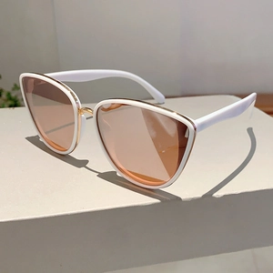 Detail shot of white cat-eye sunglasses with gold metal bridge on stone pedestal