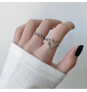 Close-up of stacked s925 silver rings with hollow heart designs on fingers