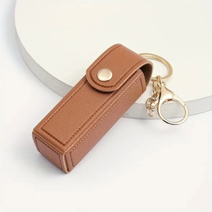Brown lychee grain PU leather lipstick holder keychain with gold buckle on white stand