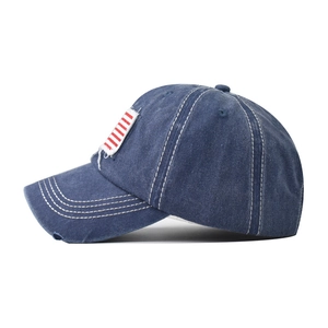 Detailed side view of washed navy cotton baseball cap with American flag patch and distressed edges