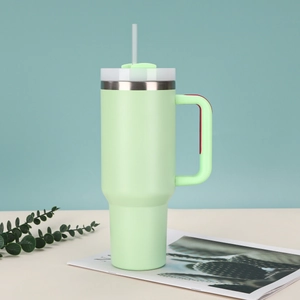 Close-up of mint green insulated 40oz tumbler with handle and straw on magazine
