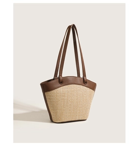 Detailed view of the woven straw texture and premium dark leather stitching on the tote