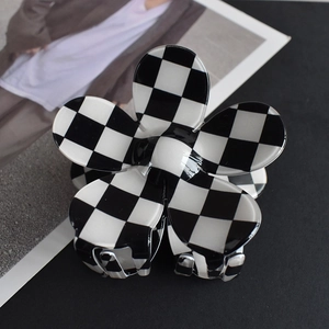 Macro detail of black and white checkerboard flower hair claw clip with acetate finish