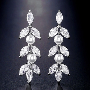 Detailopname van elegante druppeloorbellen met witte parels en marquise-geslepen kristal
