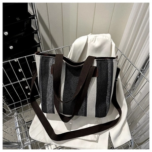 Detail of striped canvas tote bag texture with brown handles and adjustable strap