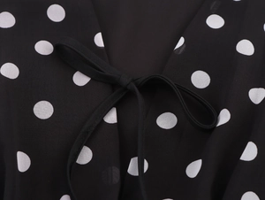Détail du col en V avec nœud papillon noir et pois blancs sur mousseline légère