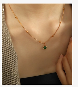 Close-up of green aventurine pendant necklace on model wearing a grey blazer