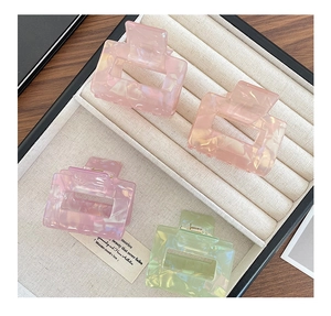 Detailed macro view of pearlescent pink and green resin hair claws in a jewelry box