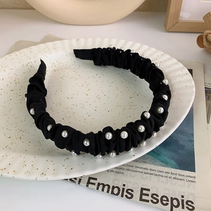 Dettaglio della fascia per capelli in tessuto nero con perle su vassoio decorato