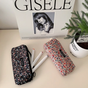 Close-up of floral corduroy stationery bags with merciparis labels on a desk