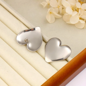 Detailed macro view of silver heart-shaped stainless steel earrings in a velvet gift box