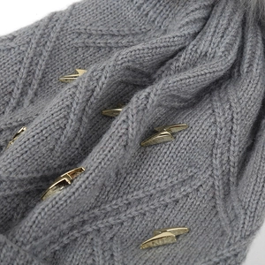 Detail of grey knitted hat featuring golden lightning studs and diamond knit texture