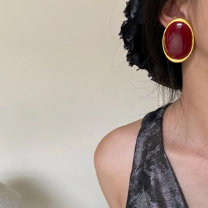 Close-up of retro oval red gemstone earrings with matte gold frames on a model