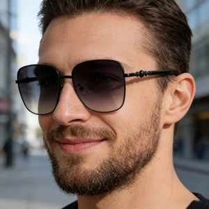 Detailaufnahme der schwarzen Metall-Sonnenbrille mit Perlendetails und grauen Gläsern