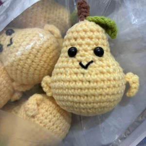 Detail of handmade crochet yellow pear dolls with cute smiles packed in a transparent bag