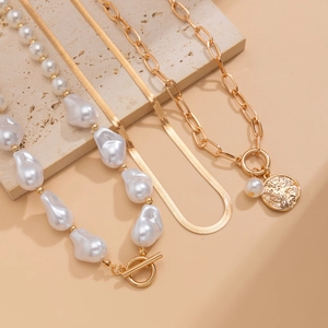 Detailed view of triple-layered gold snake chain with baroque pearl and coin pendants