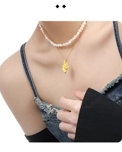 Detail of layered S925 silver necklace with irregular gold pendant and white pearl chain