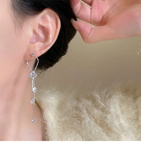 Macro shot of silver tassel earrings with sparkling crystals worn on a model's ear