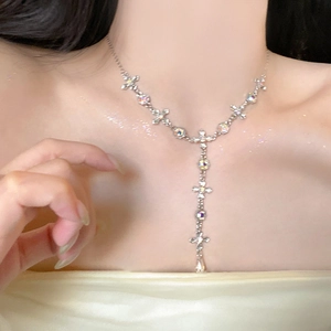 Detail of silver Y-shaped necklace with cross charms and aurora crystals on model