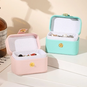 Detail of pink and mint green travel jewelry cases with cross-grain texture and metal snap