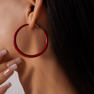 Gros plan de créoles géométriques rouge vif sur mannequin pour un look rétro tendance