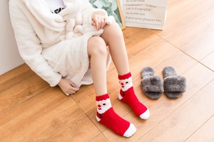 Cozy red Christmas socks with Santa Claus pattern in soft fleece, styled on wooden floor