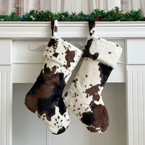 Detail of plush cow print Christmas stockings hanging on fireplace with festive decor