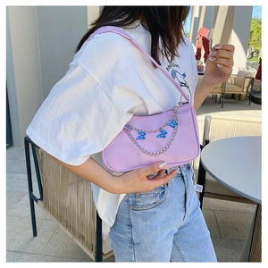 Detail of purple shoulder bag with silver chain and blue butterfly pendant decoration
